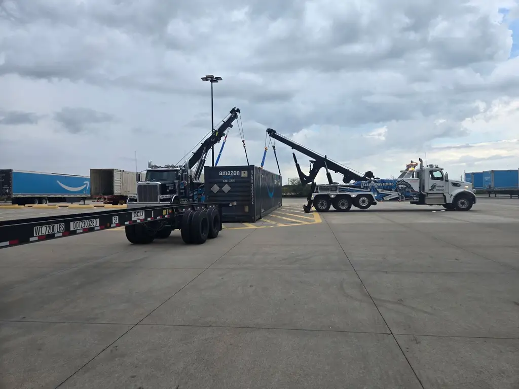 Wide view of the rotator and a second truck during a container lift at a distribution yard