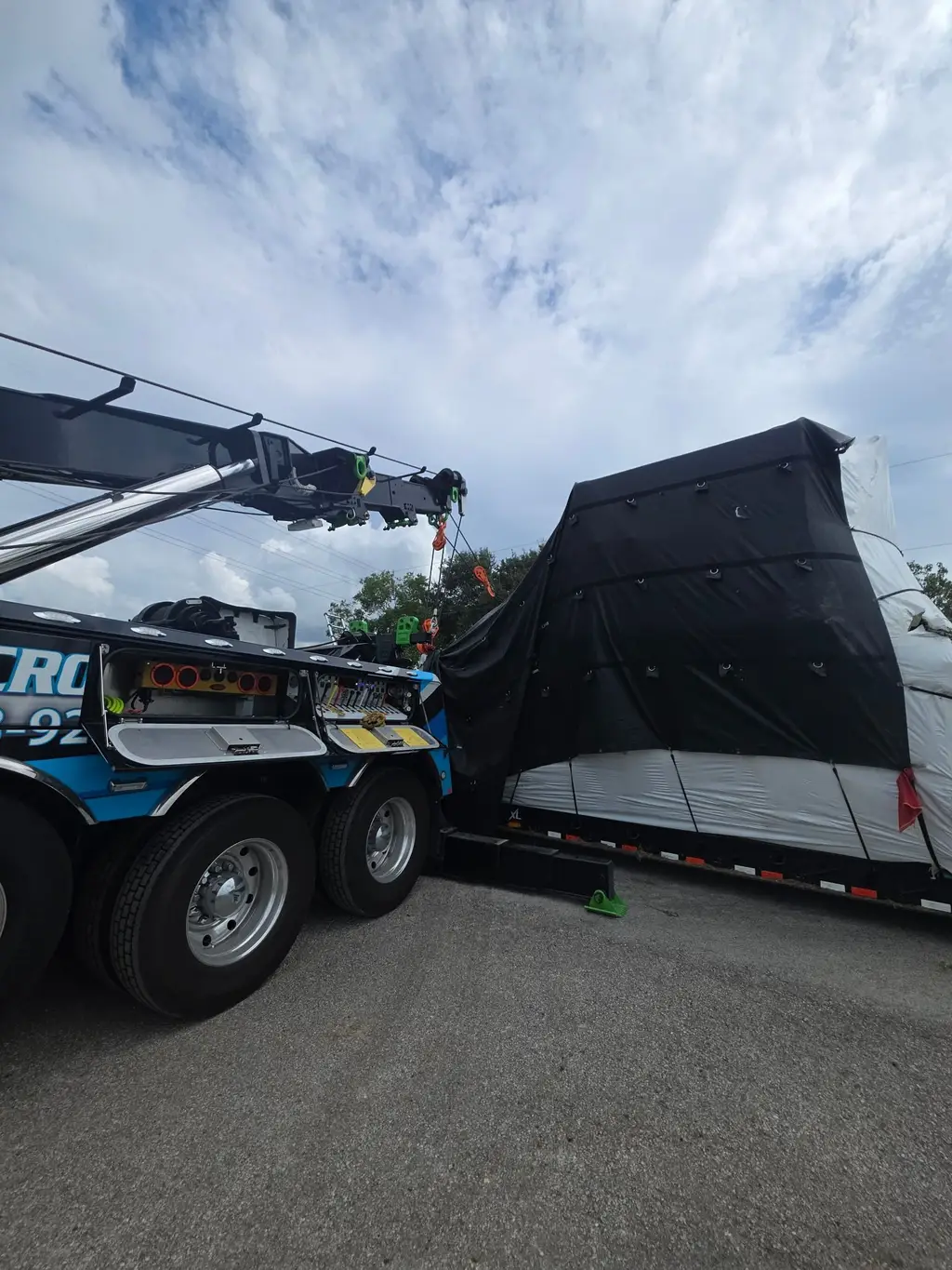 Tarped machinery being set down onto a trailer by the rotator